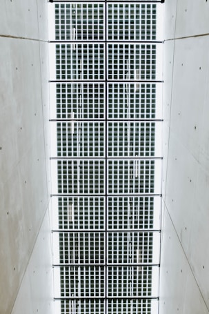 A symmetrical pattern of rectangular solar panels arranged in a grid. The panels are bordered by a light structure, and the surrounding area is a plain, smooth surface.