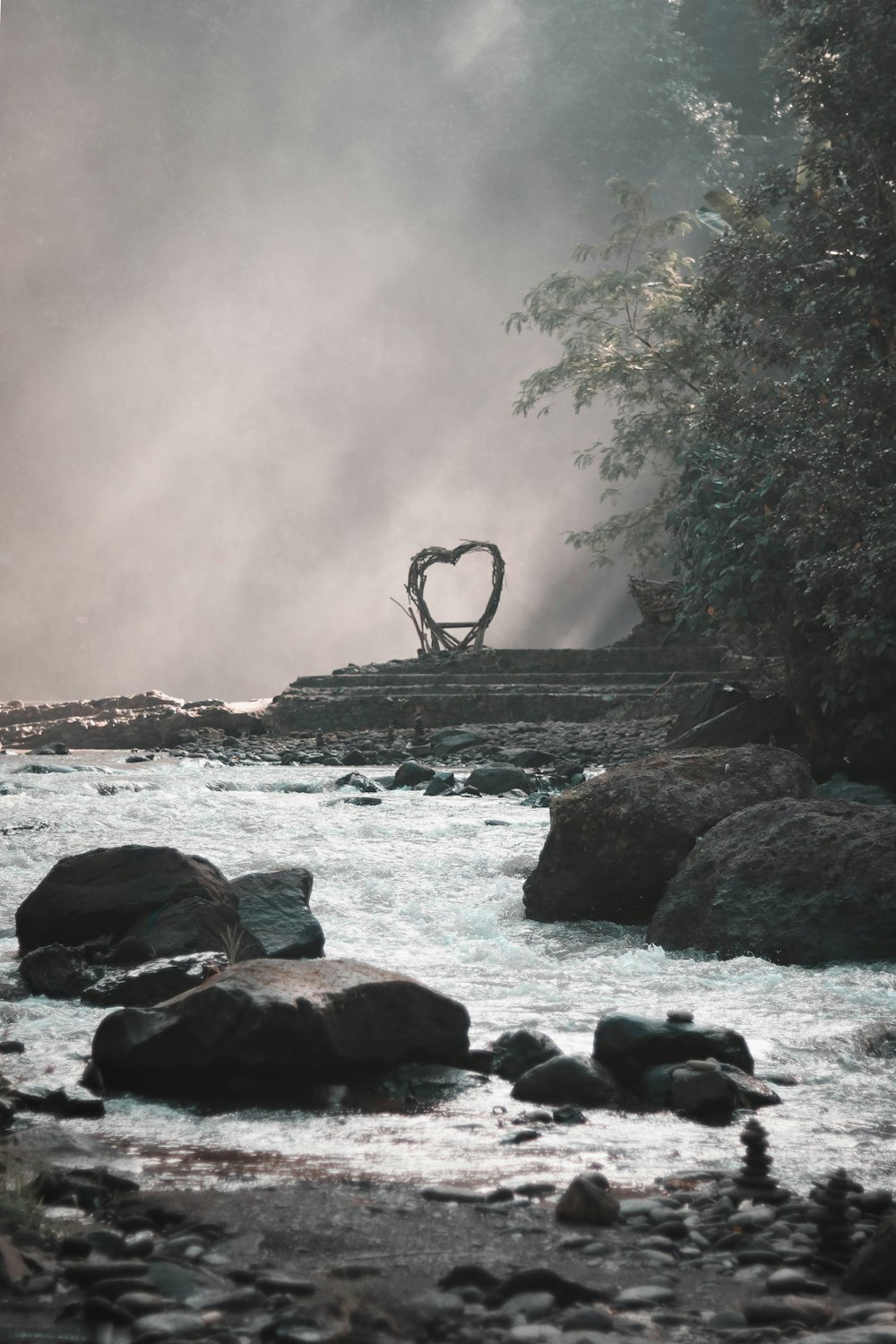 a river with rocks and a heart shaped sculpture