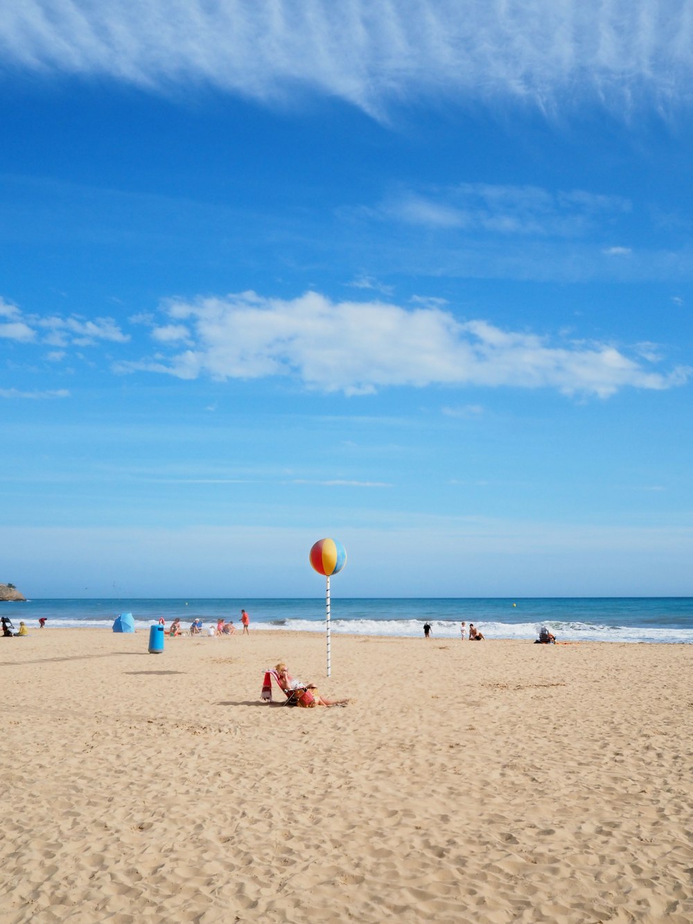 a beach with people sitting and standing on the sand