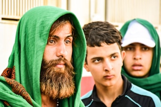 man wearing green headscarf besides man wearing black and blue polo shirt