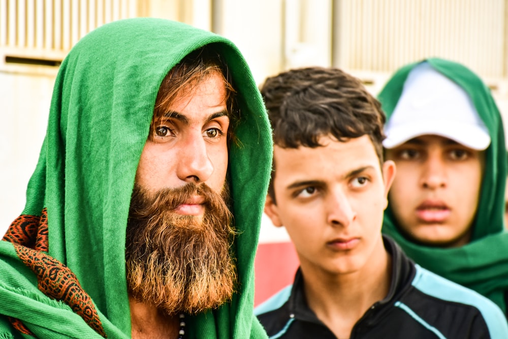 man wearing green headscarf besides man wearing black and blue polo shirt