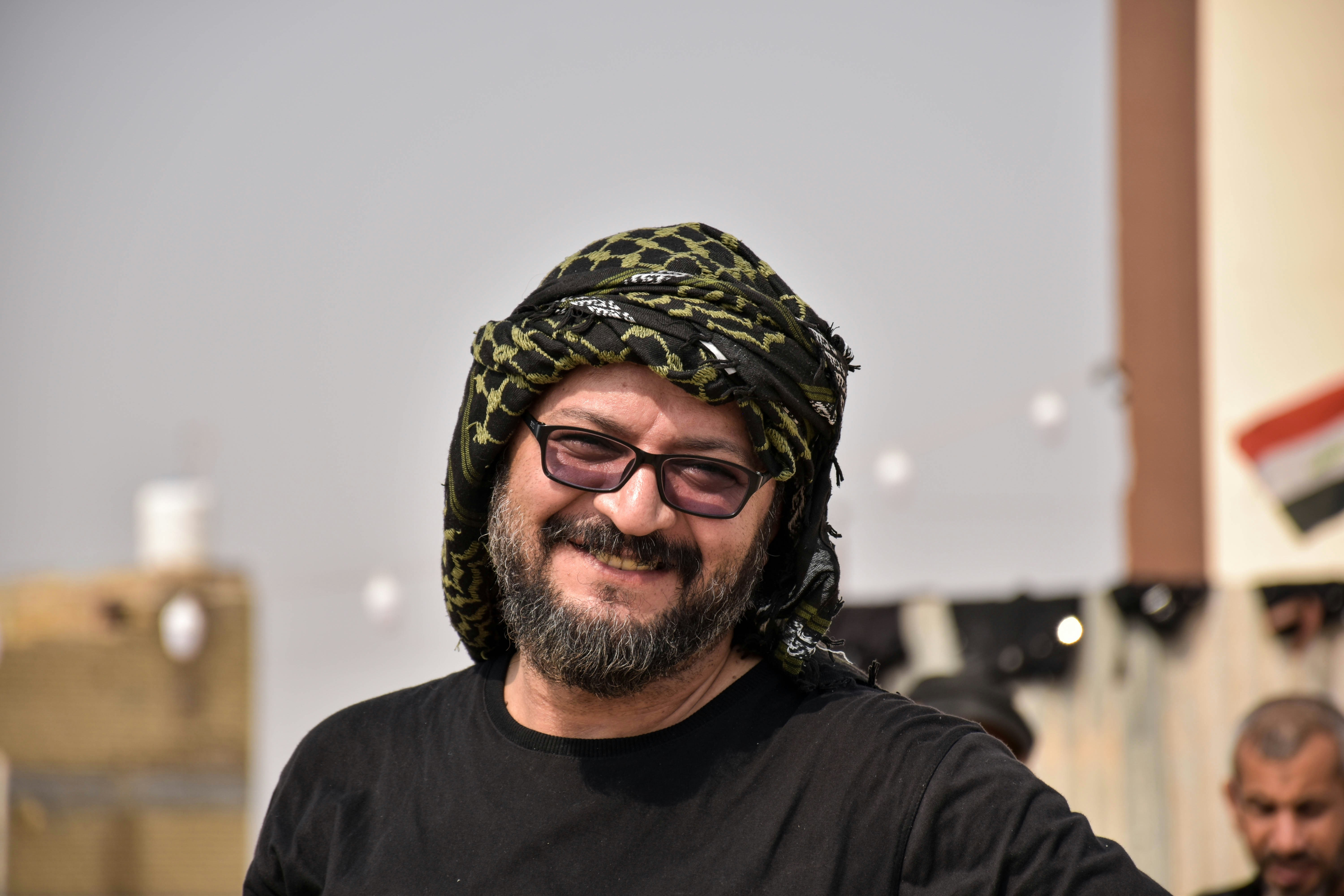 pria tersenyum mengenakan kemeja hitam