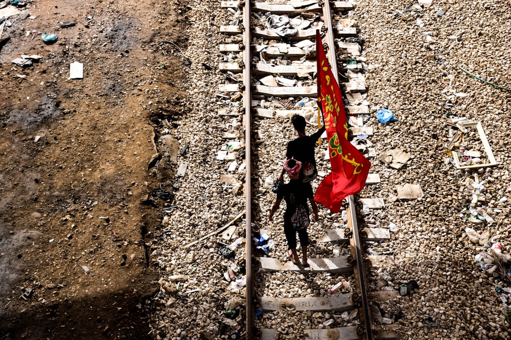 two people standing on a train track holding a red flag