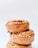 Three stacked cinnamon rolls topped with a caramel glaze and sprinkle of nuts, creating a visually appealing and delicious presentation against a plain white background.