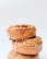 Three stacked cinnamon rolls topped with a caramel glaze and sprinkle of nuts, creating a visually appealing and delicious presentation against a plain white background.