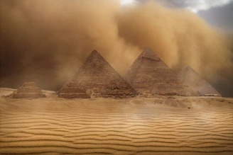 The majestic pyramids of Giza standing tall against a golden desert backdrop under a bright sun.