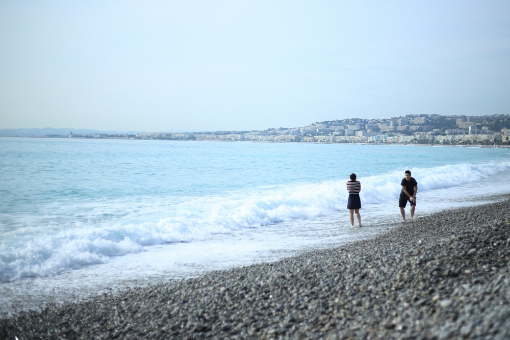 two people standing on shore