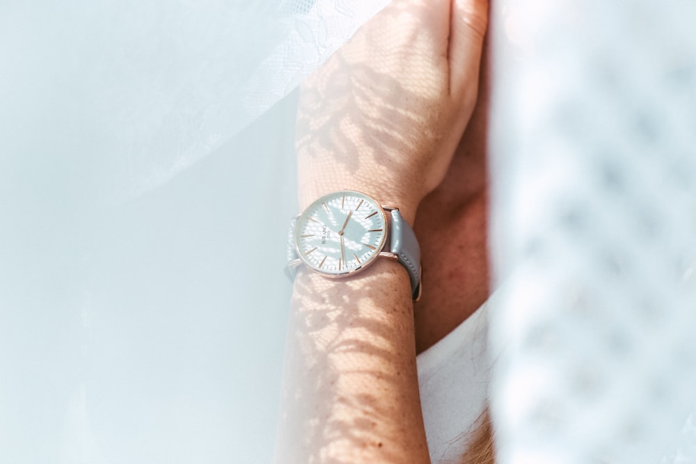 person wearing round white analog watch