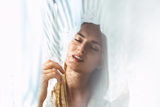 A soft-focus image of a woman’s hand tracing patterns on sheer fabric.