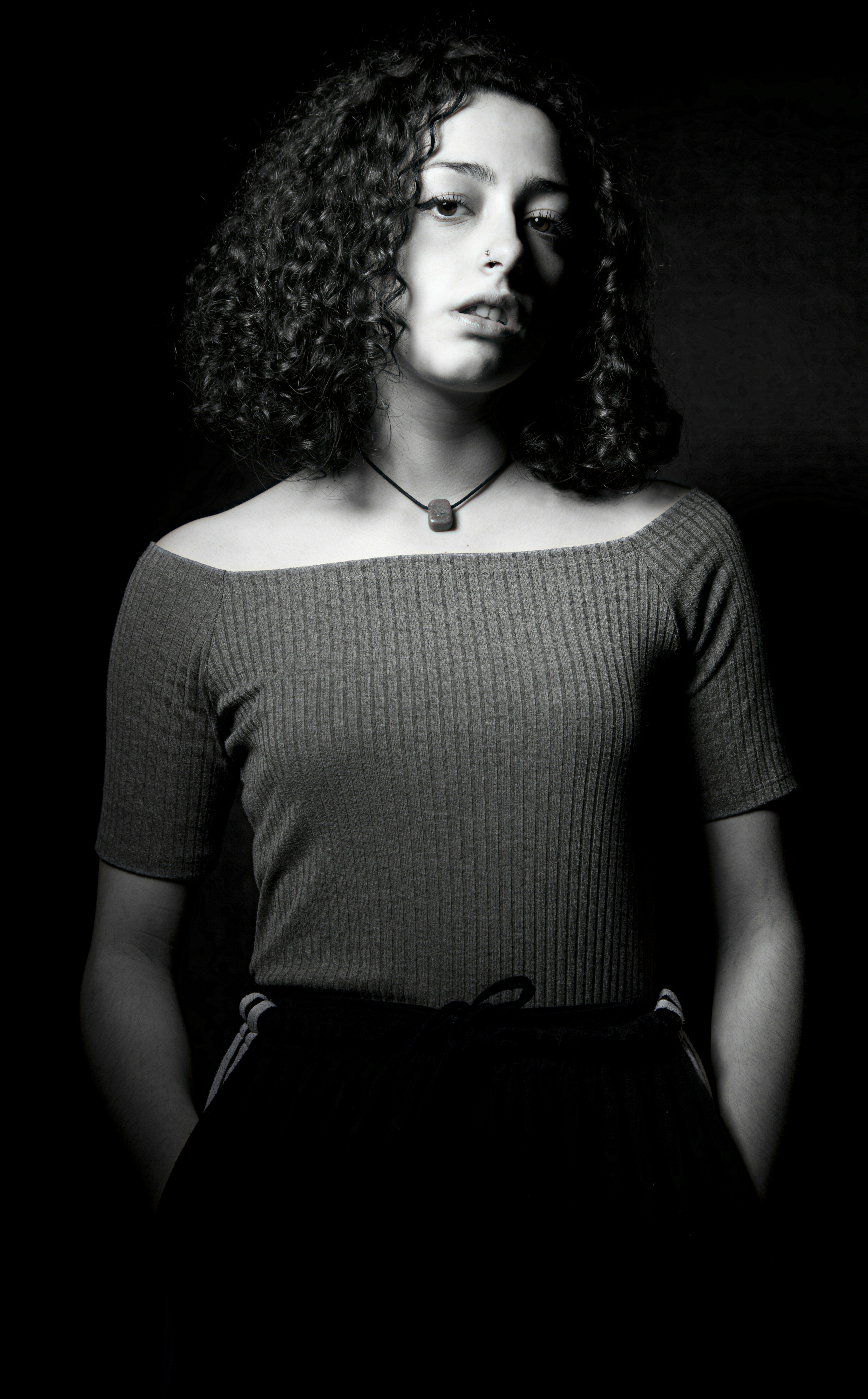 grayscale photo of woman standing on black background