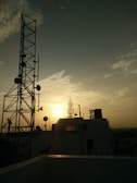 A clear city skyline with visible telecom towers and antennas at sunset.