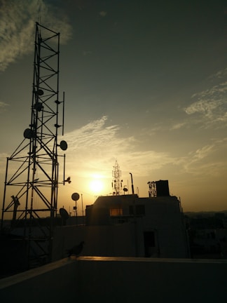 A clear city skyline with visible telecom towers and antennas at sunset.