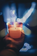person holding lighted votive candle