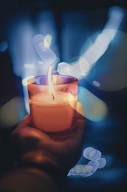 person holding lighted votive candle
