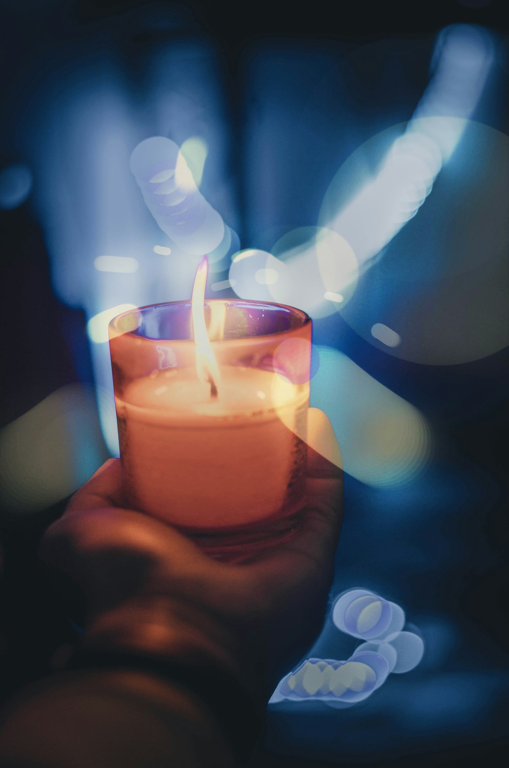 person holding lighted votive candle