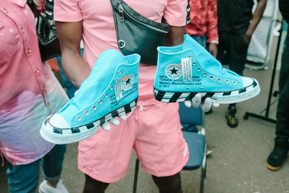 man holding blue-and-white Converse All-Star high-top sneakers