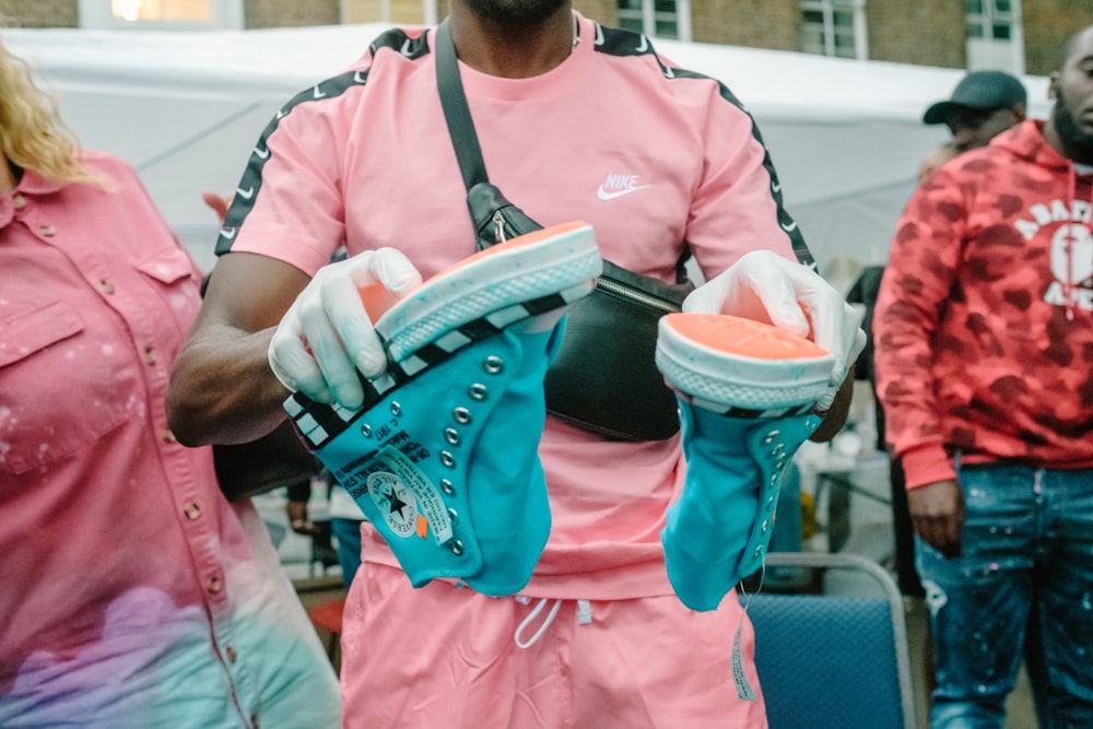 person holding pair of teal high-top sneakers