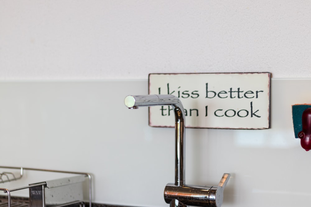 a kitchen sink with a faucet and a sign above it