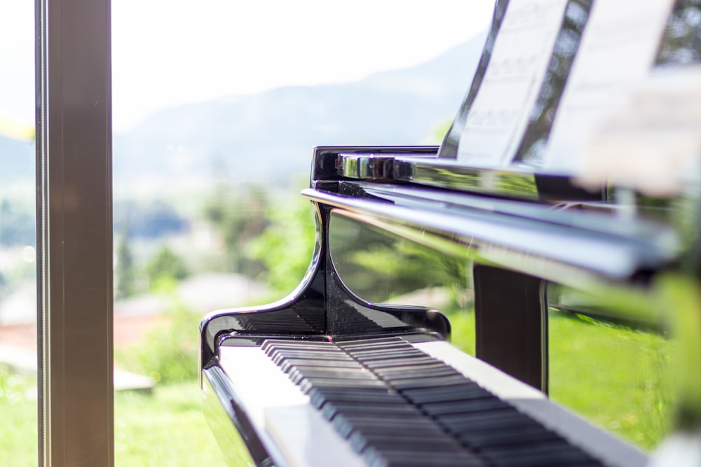 black wooden piano near glass window