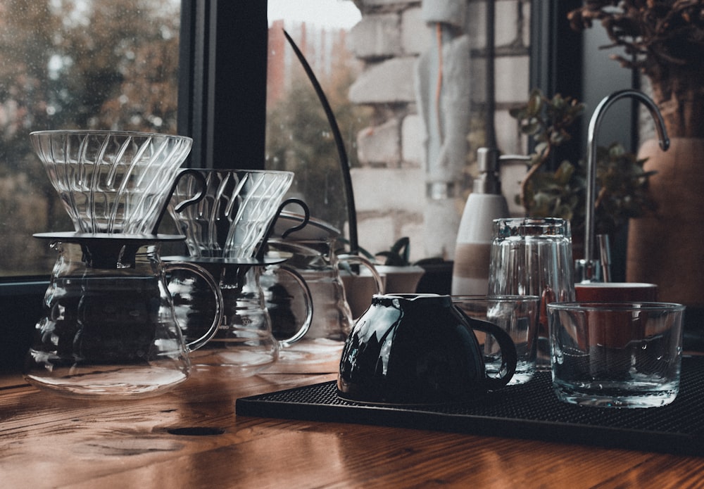 assorted mugs on wooden surface near sink faucet