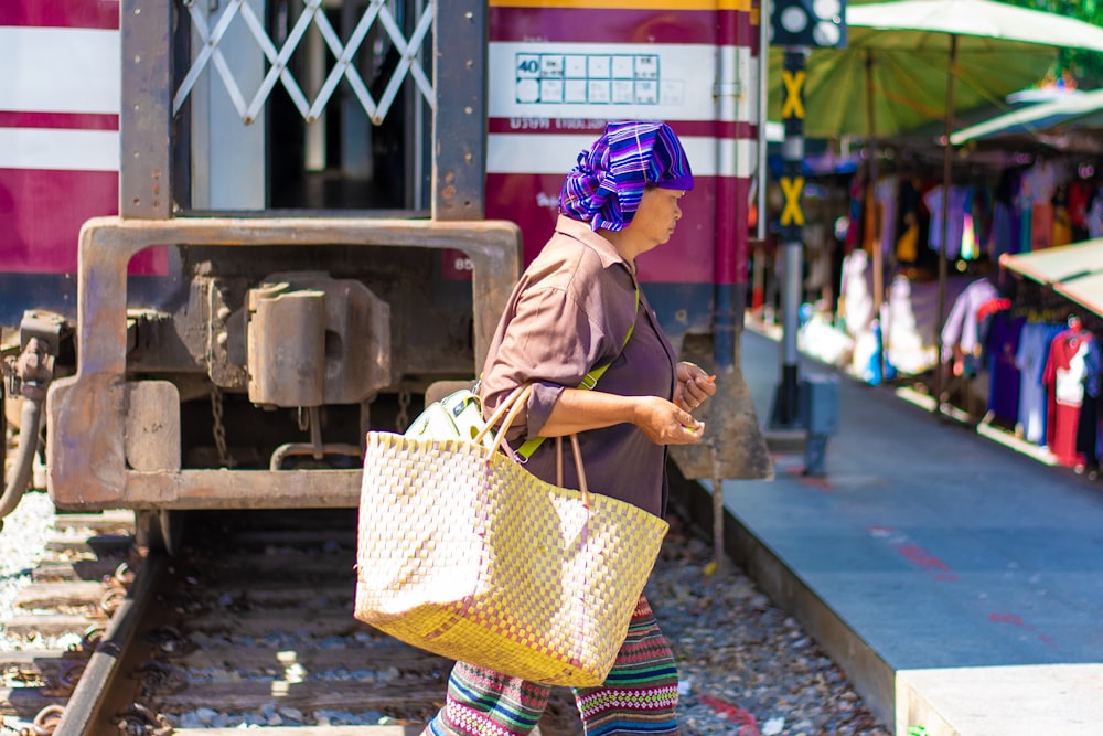 woman carrying brown wicker bag while walking on street