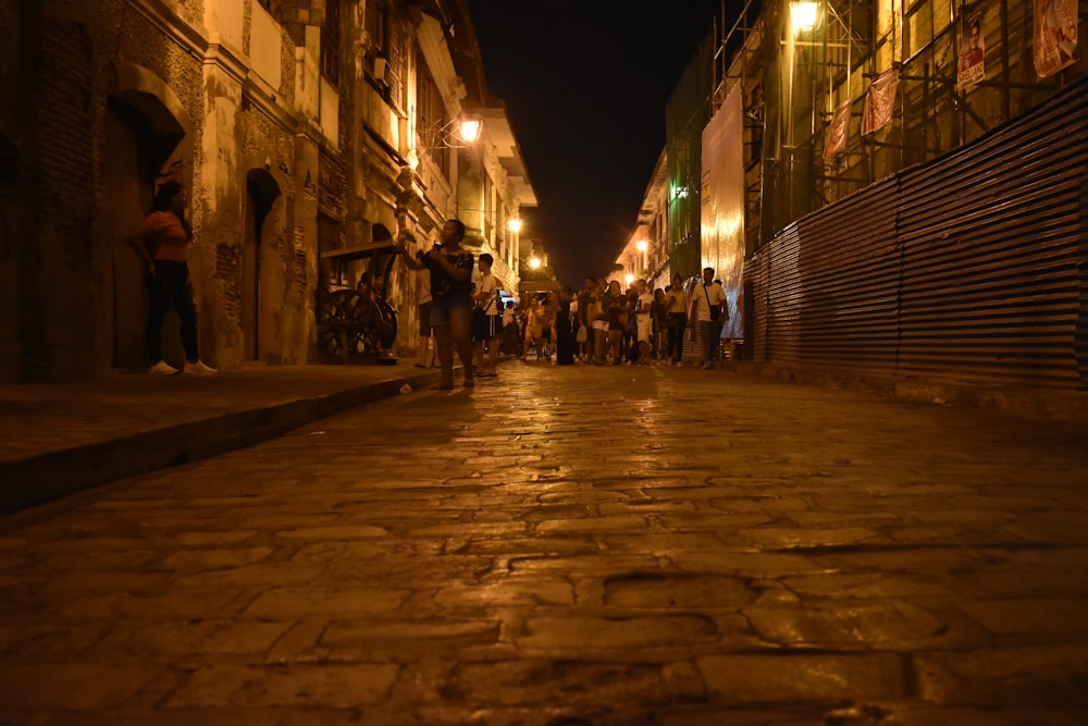 a group of people walking down a street at night