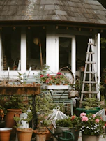 A cozy garden scene featuring outdoor cushions, plant pots, and garden tools.