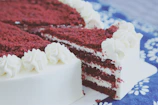 Close-up of a rich, velvety red velvet cake topped with cream cheese frosting and fresh berries.