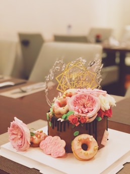 chocolate cake topped with roses and doughnuts