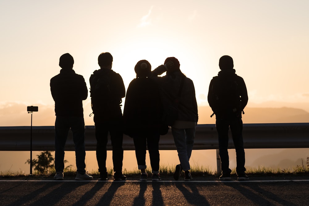 silhouette photography of people standing near road barricade