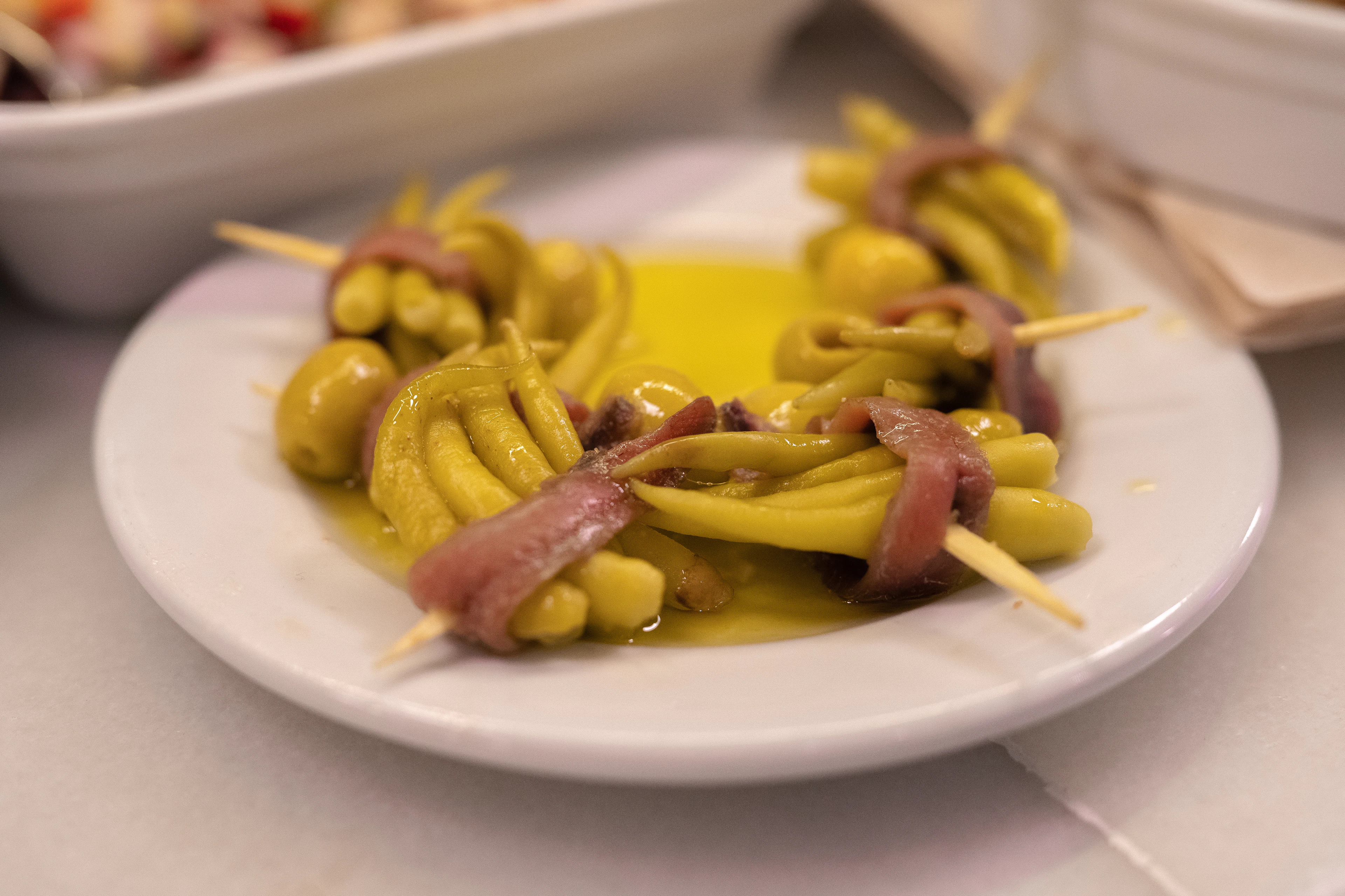 Gildas on a bar plate: green olives, guindilla peppers and anchovies threaded onto toothpicks in olive oil, the classic Basque pintxo