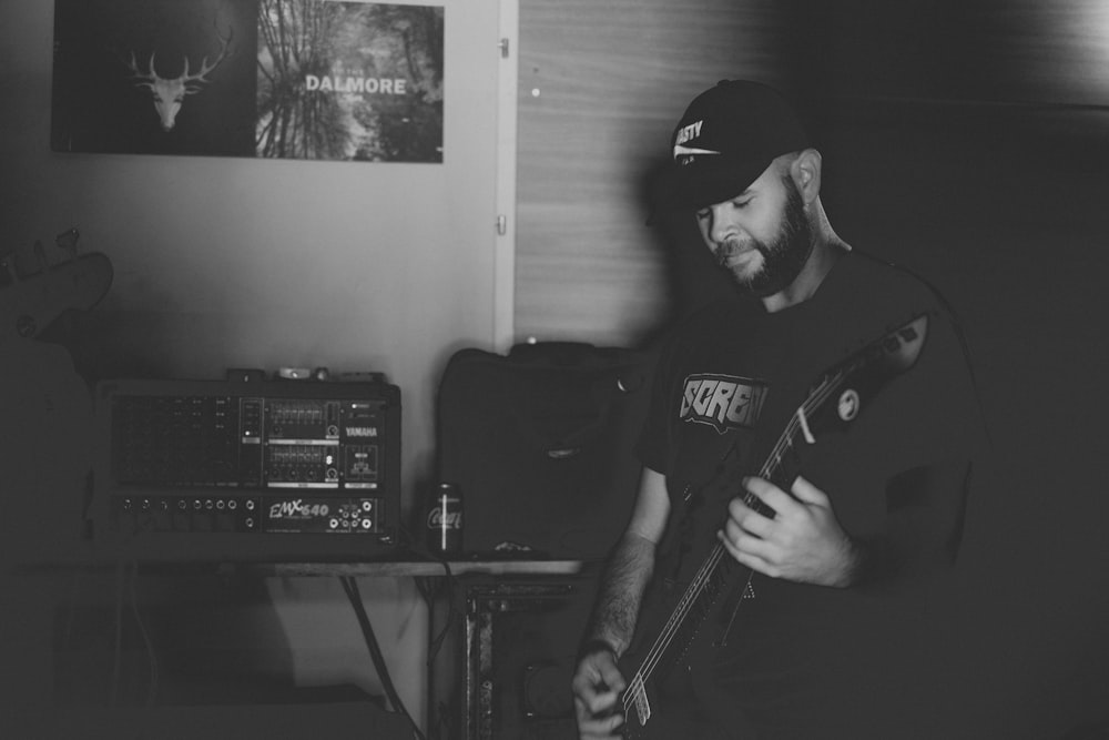 grayscale photography of man playing guitar