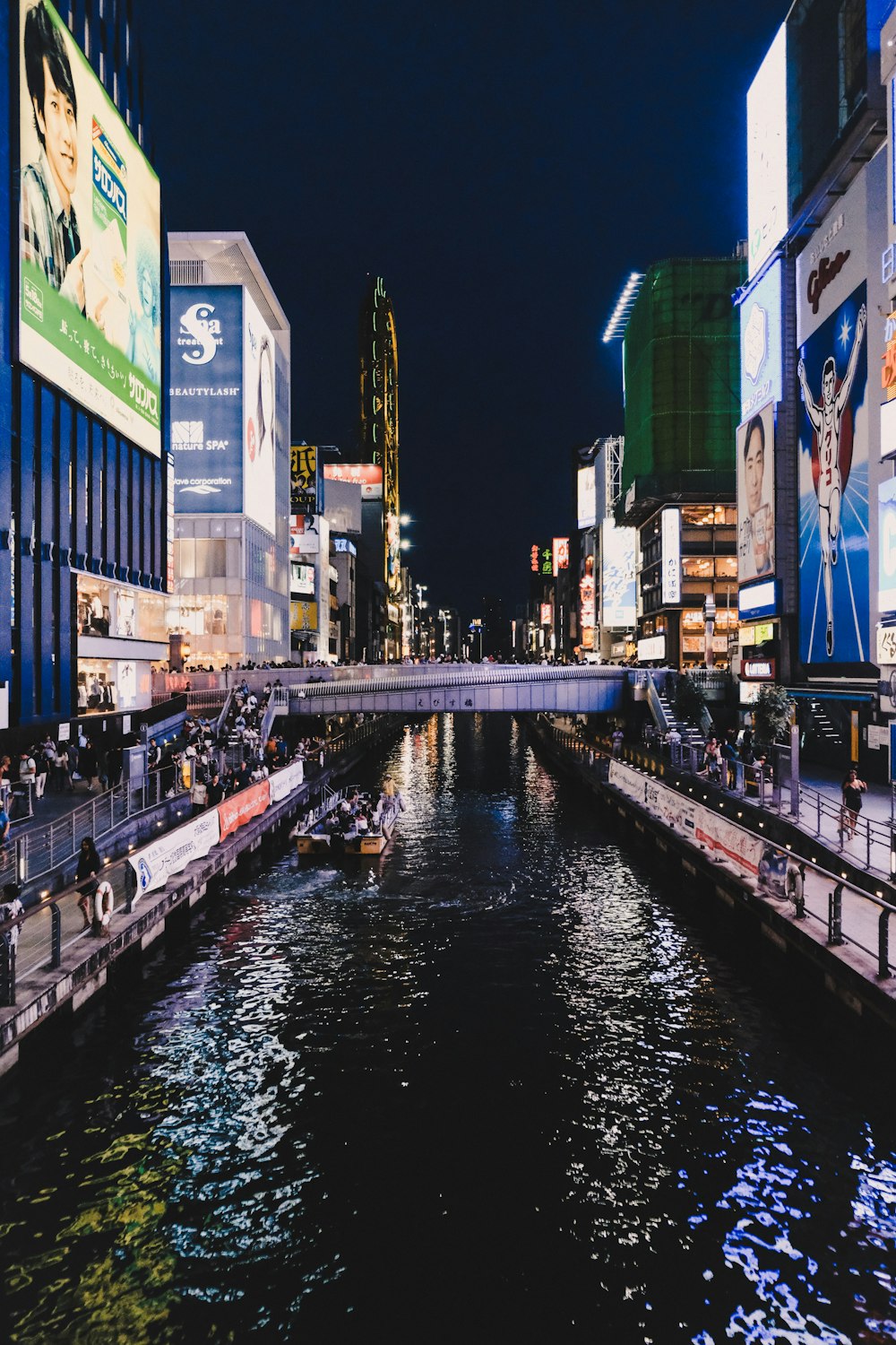 people walking near high-rise buildings viewing lake at night time