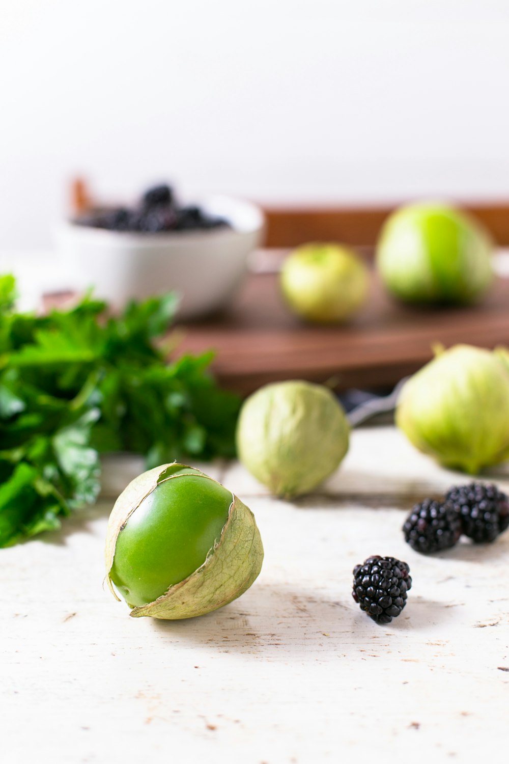 green fruit near black berry on white surface