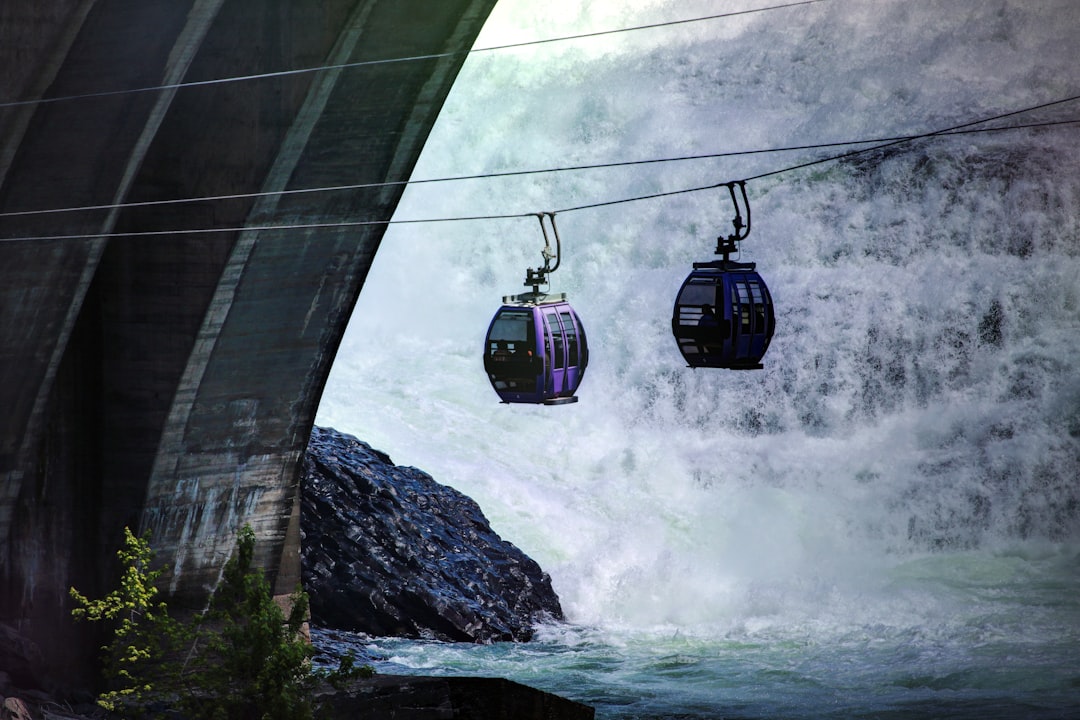 two purple cable cars over river with waterfalls