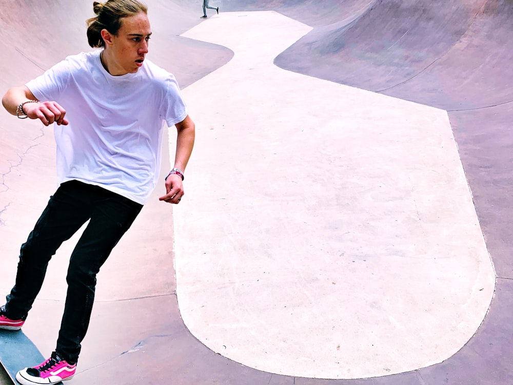 man in white t-shirt and black denim jeans on skateboard in park