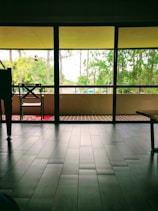 Bright, airy deluxe suite with large windows overlooking lush greenery and elegant furnishings.