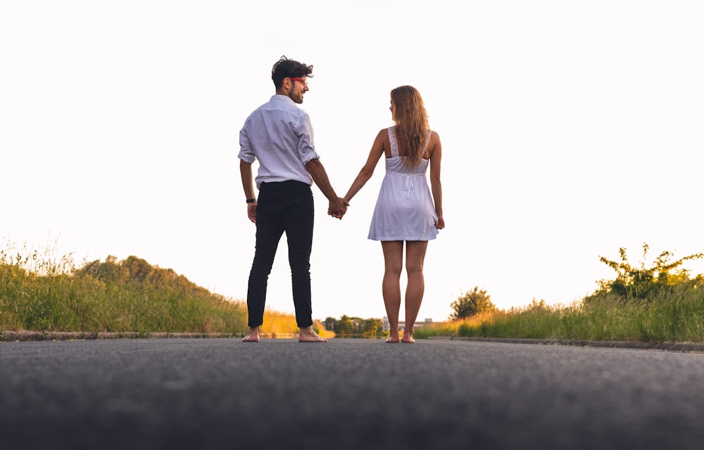 man and woman standing holding hands together while walking on road