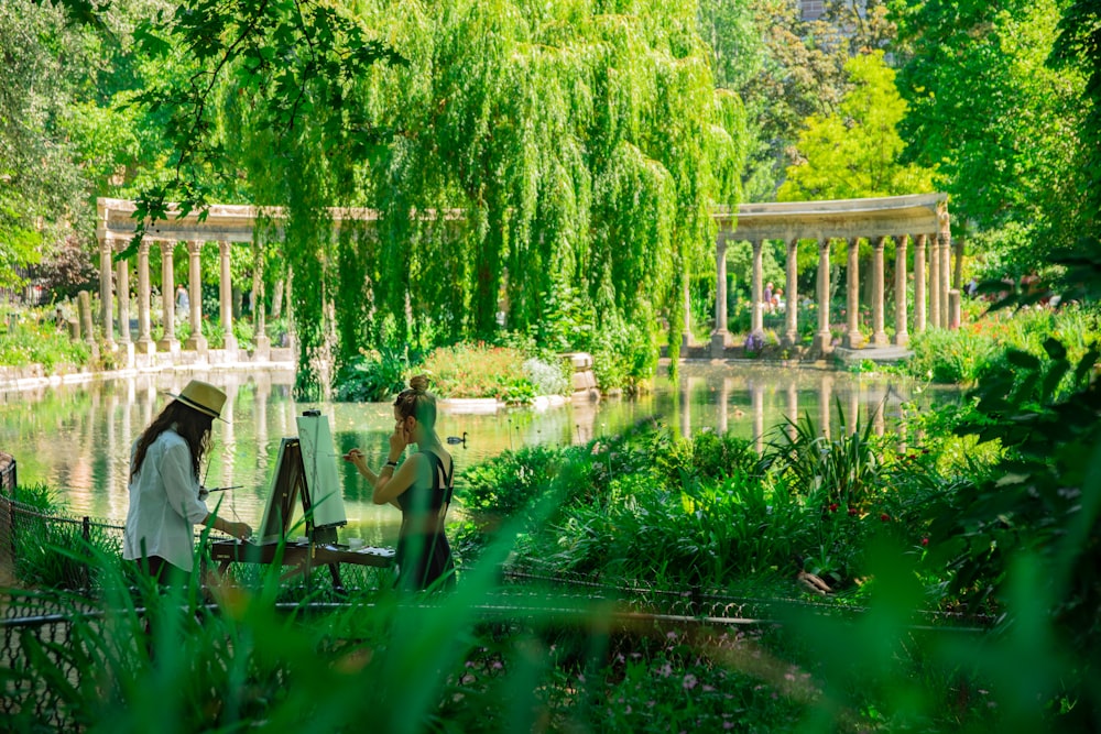 homme et femme peignant près du plan d’eau