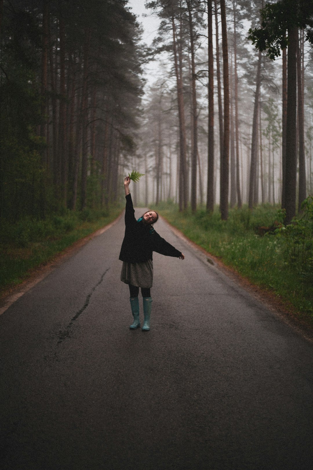 woman raising hand standing between trees