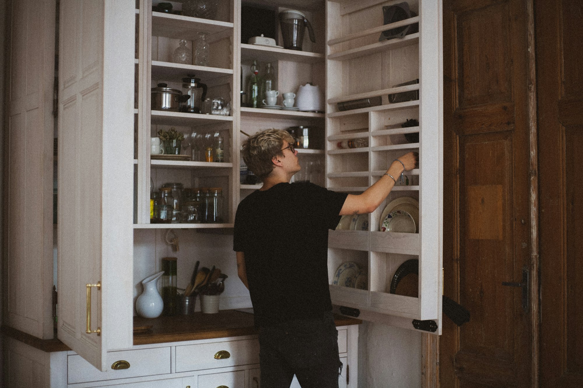 A man organizing the kitchen cupboard.