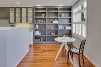 A stylish industrial pipe shelf paired with a white farmhouse side table in a sunlit room.