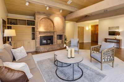 a living room with a brick surround fireplace and neutral colored walls and furniture 