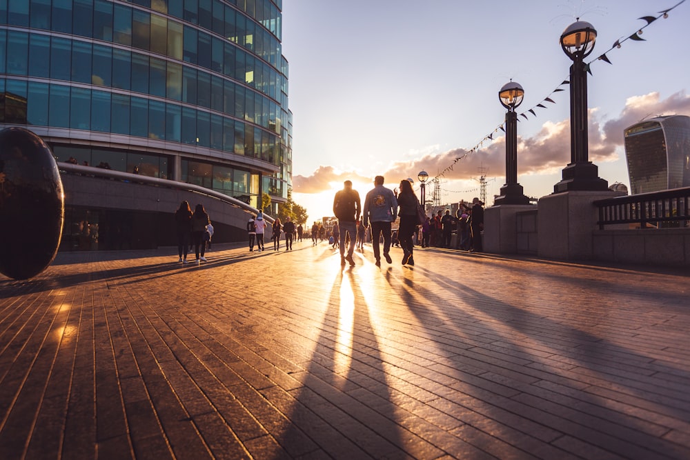 three people walking near high-rise building during sunset