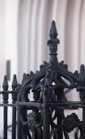 A black wrought iron fence with decorative elements surrounding a home.