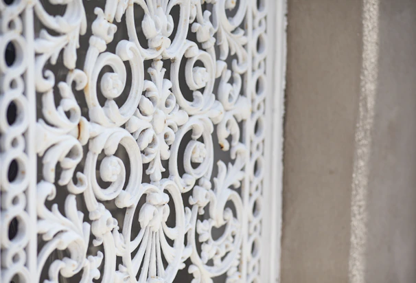 Close-up of a handcrafted wrought iron window grille with intricate floral patterns against a black background.