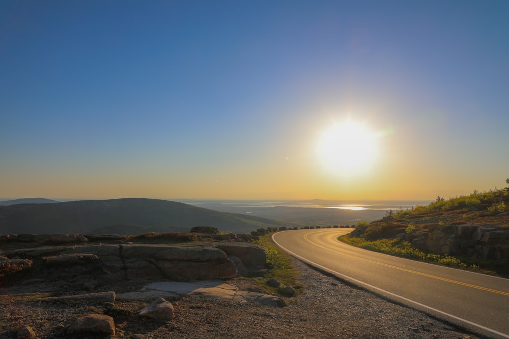 road, grass, and rocks during golden hour