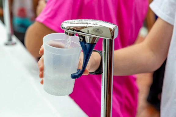 person filling white plastic cup with water