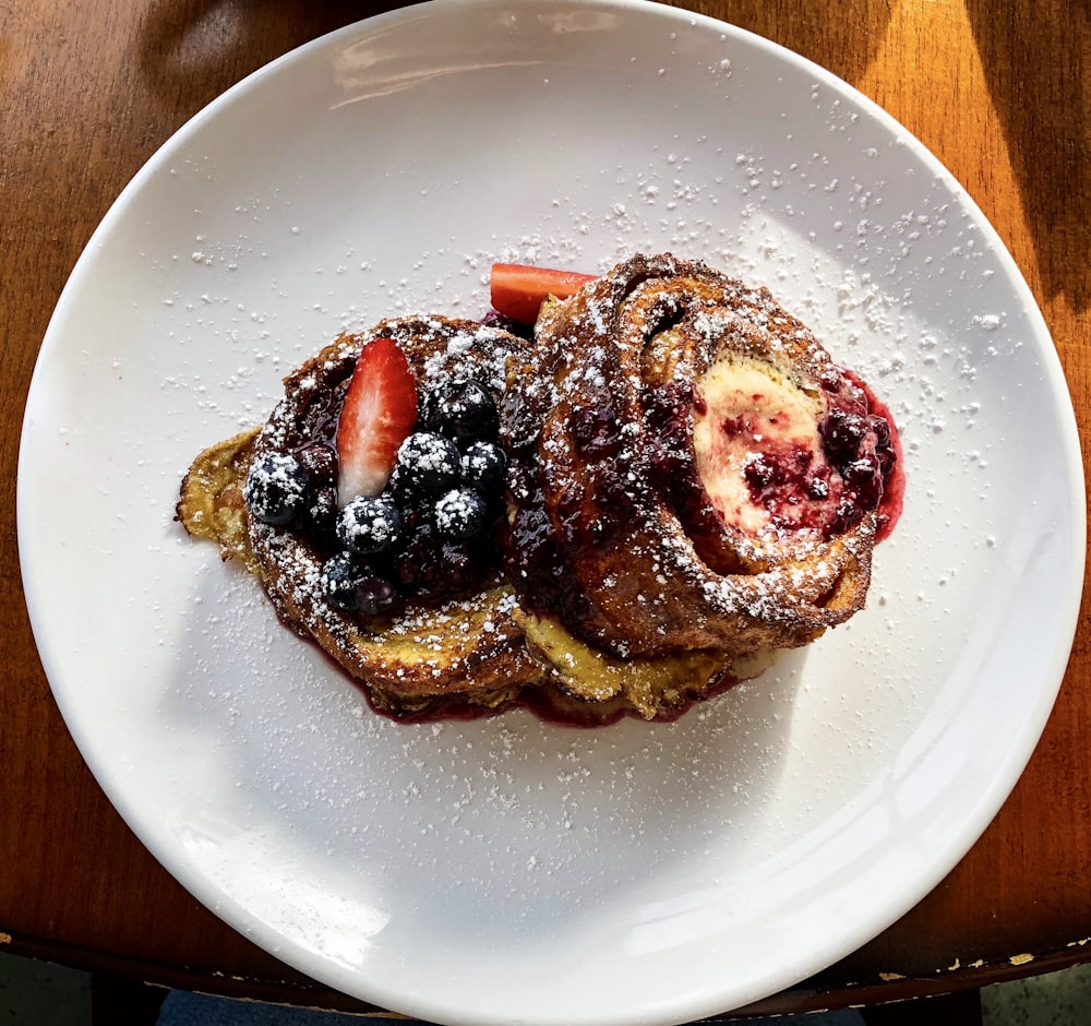 pastry with sliced strawberry and blueberries on plate