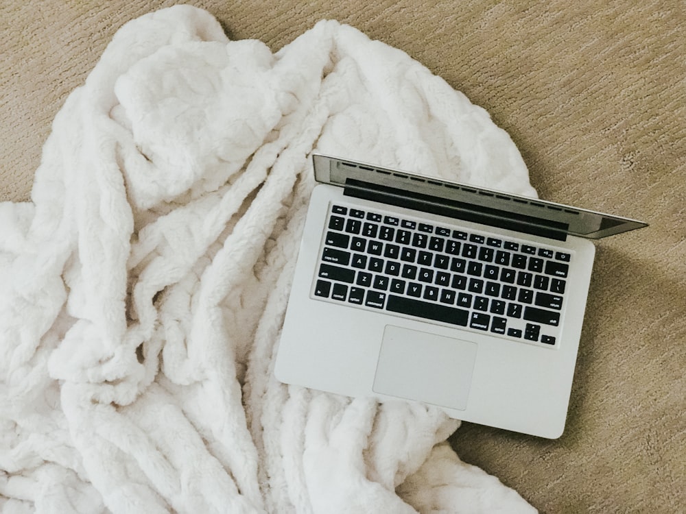 MacBook on white comforter